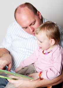 Father and baby daughter reading
